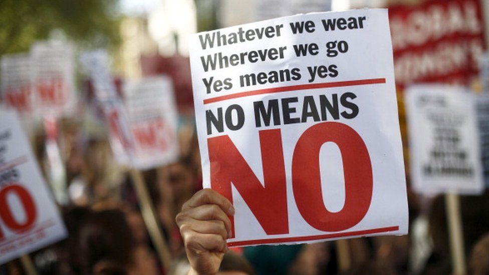 People holding placards saying "Whatever we wear
Wherever we go
Yes means yes 
No means No"